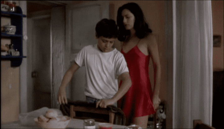 Fernanda Serrano wearing a red sleeveless dress and Saúl Fonseca wearing a white t-shirt in a scene from the 1999 film, Jaime