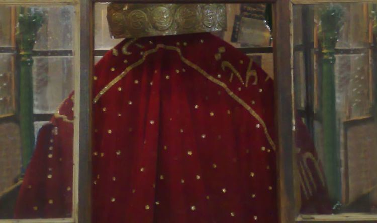 The tomb of Jalaluddin Surkh Posh Bukhari is encased inside a brown wooden glass case with a red Altar cloth and a copper relic on top with a circular pattern.