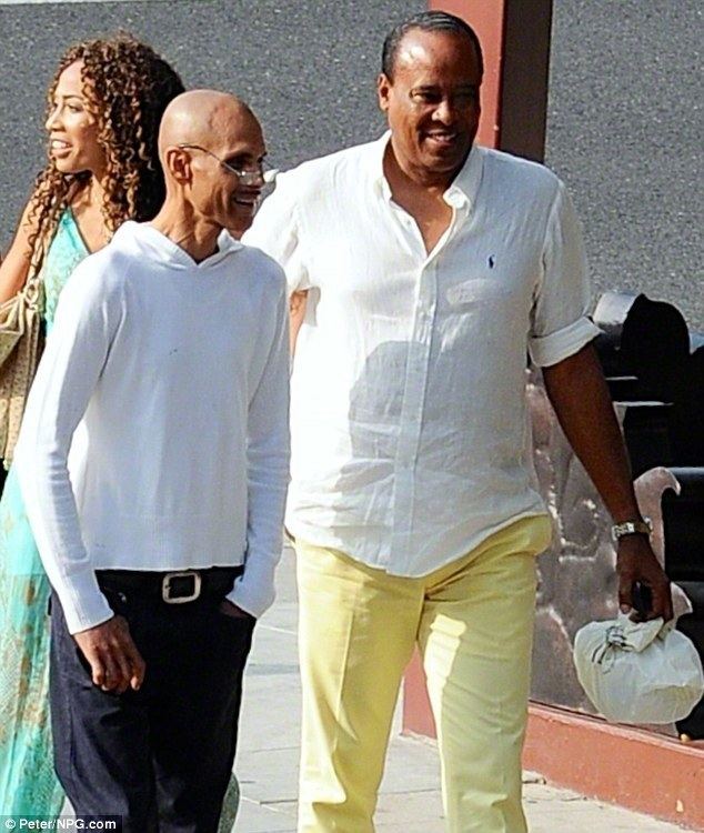 James DeBarge smiling while wearing a white sweatshirt and eyeglasses while Dr. Conrad Murray wearing white long sleeves and yellow pants