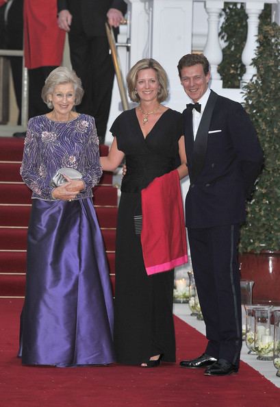 James Ogilvy smiling with Princess Alexandra and Julia Ogilvy while he is wearing a black coat, white long sleeves, black pants, and bow tie