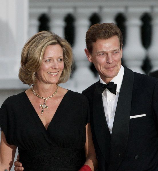 James Ogilvy smiling and wearing a black coat, white long sleeves, and black bow tie while Julia Ogilvy wearing a black dress and necklace