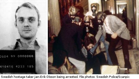 Jan-Erik Olsson (left image) seriously looking while holding black cardboard with numbers on it, he is wearing a polo long sleeve in an old photograph. In the right image, Jan-Erik sitting down on the carpet wearing a long sleeve and pants and was being held by 5 men wearing a coat and pants and with gas masks inside at the Kreditbanken bank
