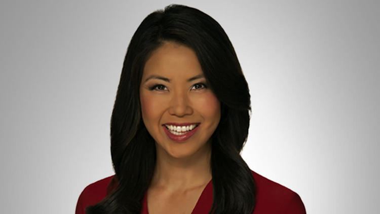 Janelle Wang smiling and wearing a red sleeve in white background