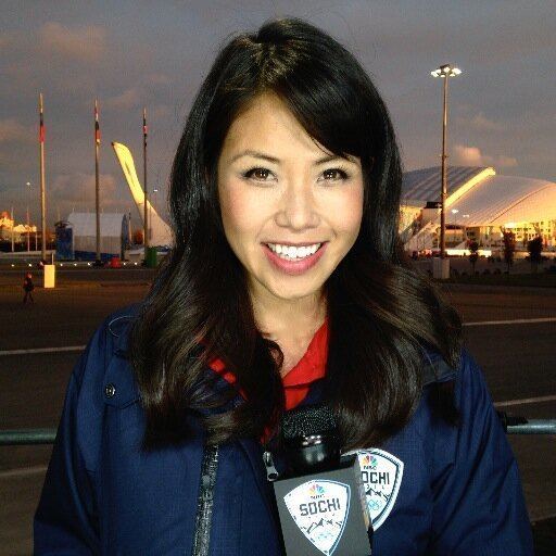 Janelle Wang smiling and holding a microphone while wearing a jacket outdoor