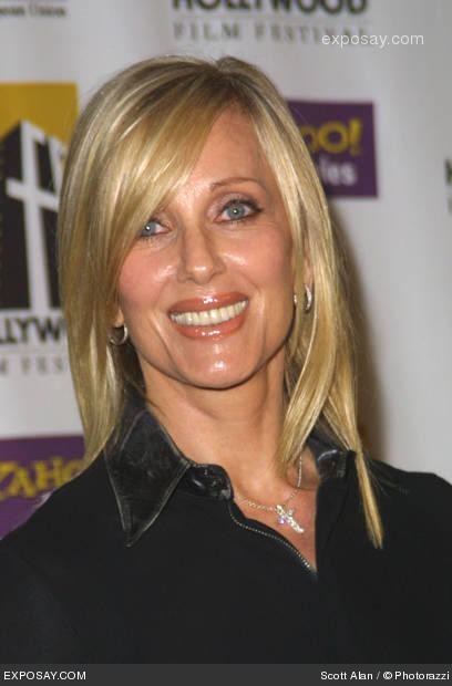Janice Pennington smiling while wearing a black blouse with collar, earrings, and necklace