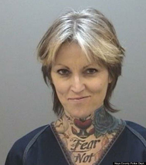 Janine Lindemulder is smiling, has black highlighted hair, a tattoo on her neck saying ‘Fear Not” and roses, wearing a blue top.