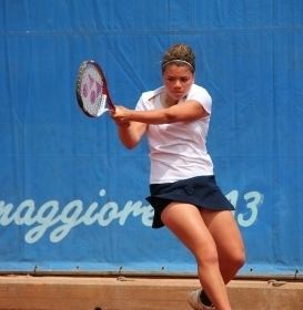 Jasmine Paolini playing tennis while wearing a white shirt and black skirt