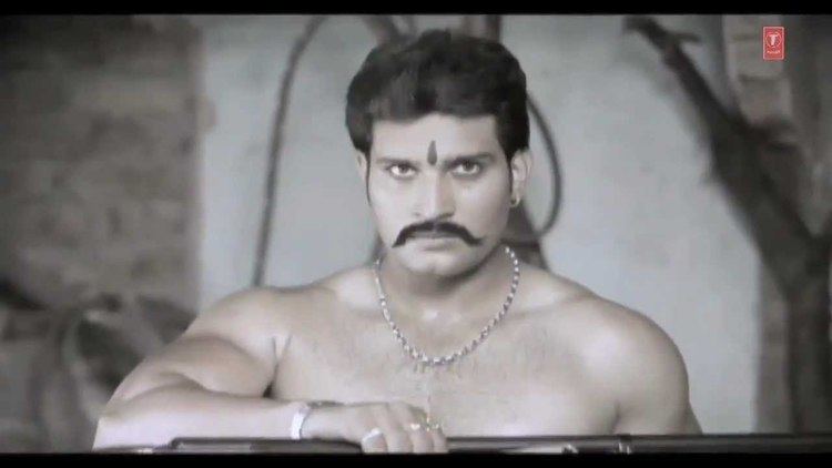 Naina Devi Jeona Morh is serious, has black hair and a mustache, has a bindi on his forehead, wearing a necklace, bracelet, and ring on his right hand, topless.