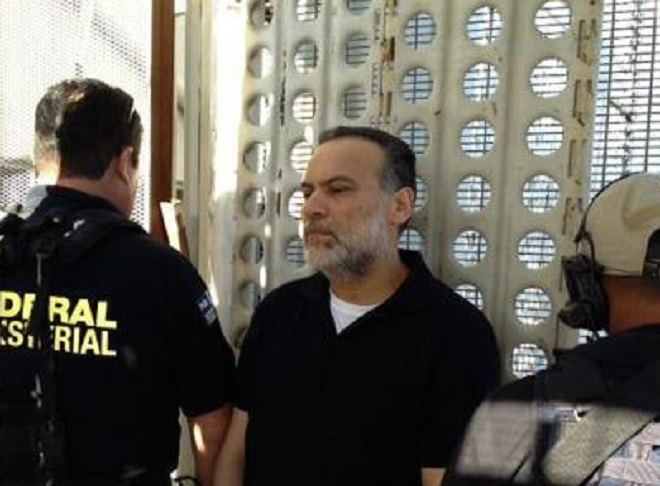 Javier Torres Félix is surrounded by two ICE agents while he is wearing a black polo shirt