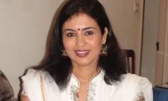 Jayashree with a smiling face, wearing earrings, and a white dress.
