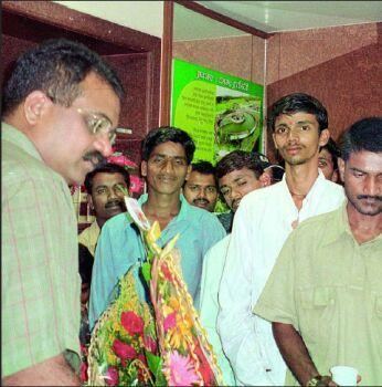 Jayendra Thakur wearing eyeglasses and a green polo shirt while surrounded by people.
