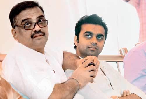Jayendra Thakur with a mustache, wearing eyeglasses and a white polo shirt with his son Rohan Jaye Thakur with a serious face and wearing white long sleeves.