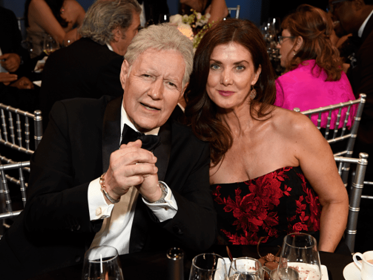 Alex Trebek and Jean Currivan Trebek smiling on their seats at a dining table during the 47th AFI Life Achievement Award in Hollywood, California.