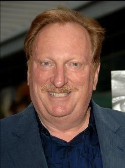 Jeffrey Jones smiling and standing while wearing a formal suit