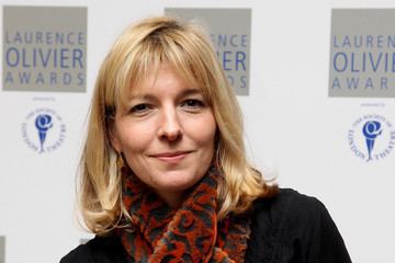 Jemma Redgrave smiling in a short hair and wearing a black coat and orange scarf