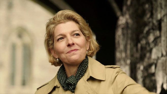 Jemma Redgrave smiling and wearing a brown coat with a polka dot scarf