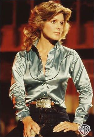 Priscilla Presley as Jenna Wade looking afar while wearing a light blue long sleeve blouse in a scene from the 1978 tv series Dallas