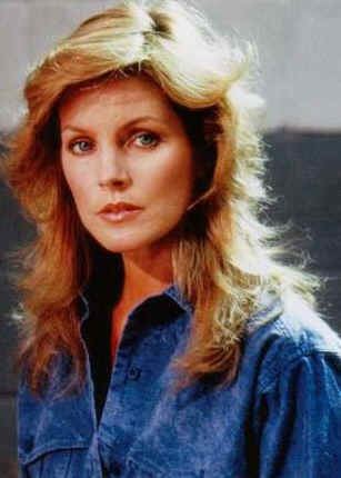 Priscilla Presley as Jenna Wade with wavy hair while wearing a blue blouse