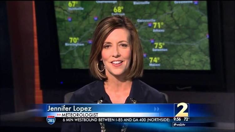 Jennifer Lopez (meteorologist) is on the television, smiling, with short hair and wearing a blue blouse.