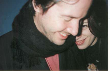 Jennifer Syme smiling with Keanu Reeves while wearing a black jacket