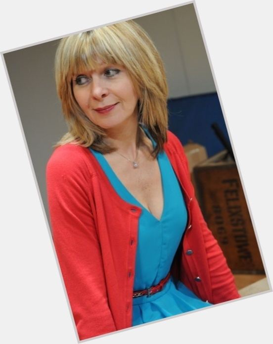 Jenny Funnell with blonde hair and wearing a necklace, cardigan, and a blue dress.