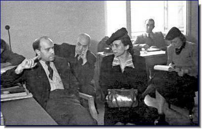 Jenny-Wanda Barkmann sitting on the chair and talking to her lawyers during her trial while wearing a hat and a blouse with a collar