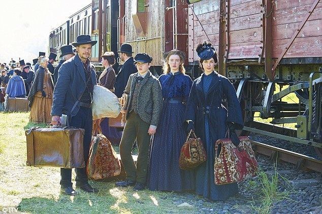 Jessica Raine, Hans Matheson, Sam Bottomley, and Amy James-Kelly carrying their suitcase near the train in the 2016 tv series Jericho