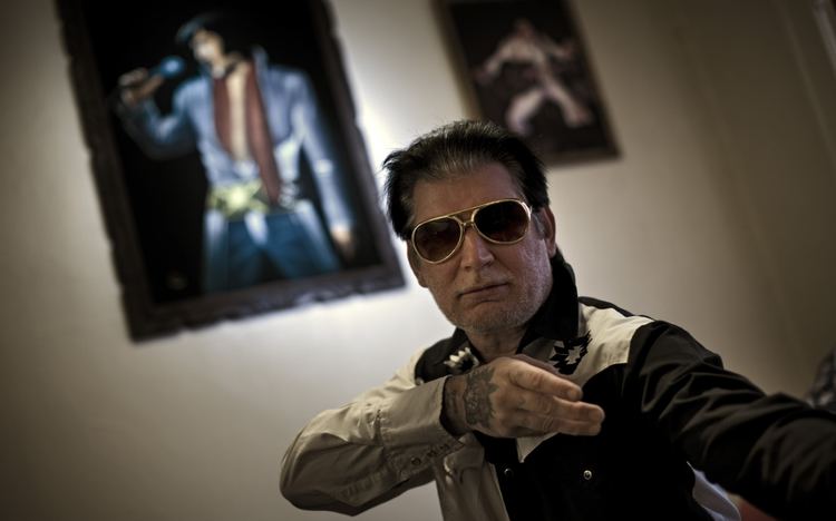 Jesco White dancing while wearing a white and black sleeve and shades