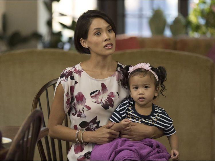 Jessalyn Wanlim carrying a toddler in a scene from the 2017 tv series, Workin' Moms