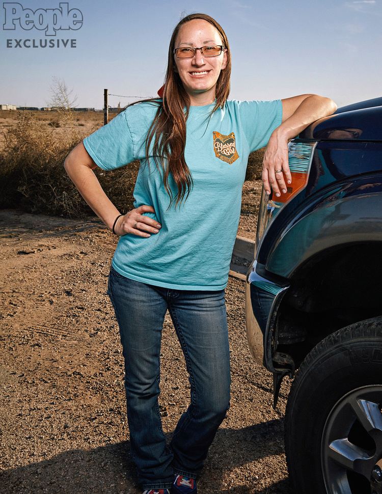 Jessica McClure smiling while wearing blue shirt, jeans and eyeglasses