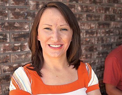 Jessica McClure smiling and wearing white and orange blouse