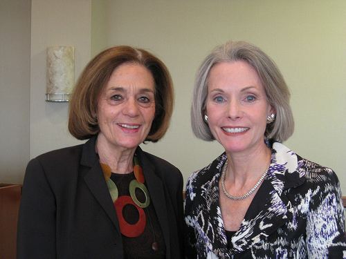 Jill Dougherty smiling and wearing a black and white coat with a silver necklace and earrings with Schemel Forum director Sondra Myers wearing a black shirt under a black coat and colored necklace