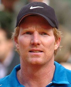 Jim Courier wearing a blue shirt and a black Nike hat