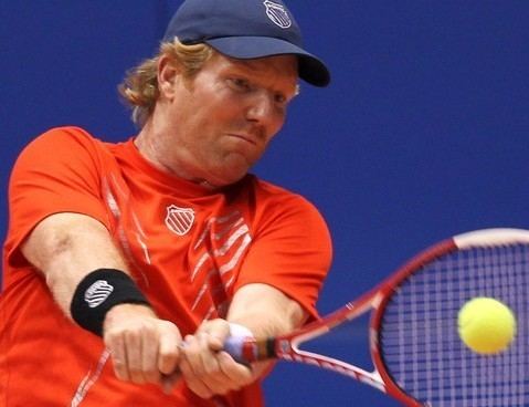 Jim Courier while playing tennis wearing an orange sportswear and a hat