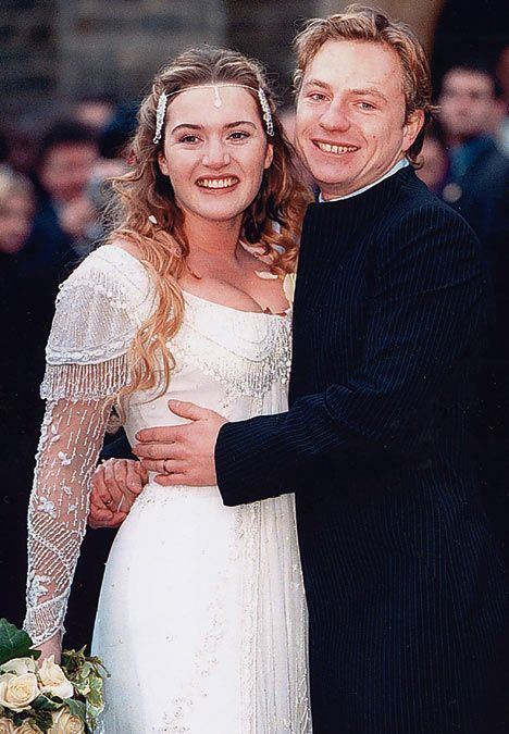 Jim Threapleton wearing a black suit and Kate Winslet wearing a wedding gown on their wedding day with a smile on their faces.