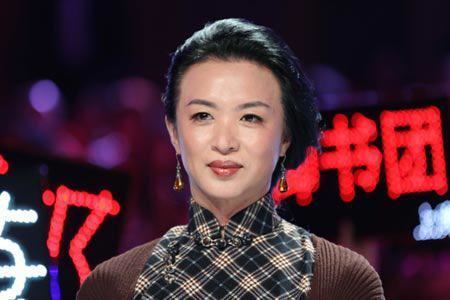 Jin Xing wearing earrings and a brown and checkered black shirt.