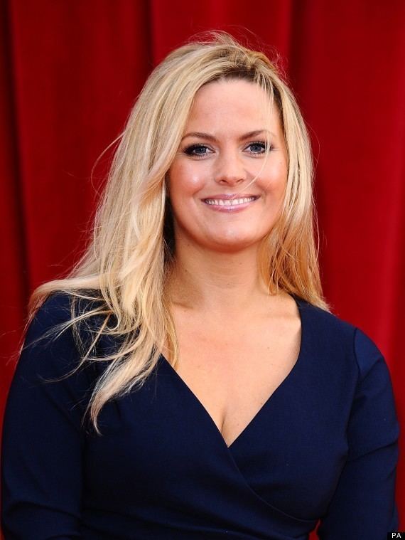 Jo Joyner smiling with blonde hair, at the British Soap awards 2011, while wearing a dark blue dress with a low-cut neckline