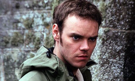 Joe Absolom with a serious face while wearing a green jacket