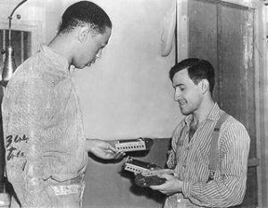 Joe Arridy happily playing with toy trains with a prison inmate and wearing striped prison clothes.