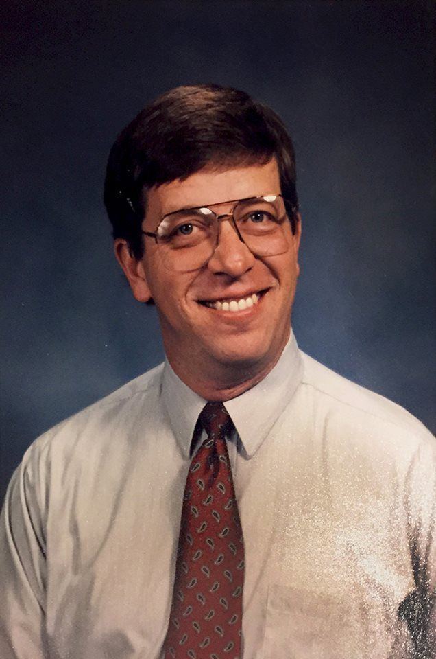 Young Joe Kenda wearing white shirt and glasses