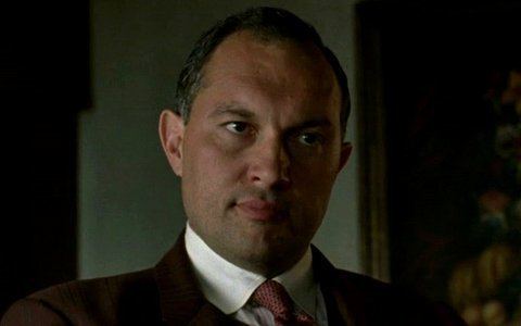 Joe Masseria as portrayed by Ivo Nandi wearing a brown suit and a red tie in a scene from Boardwalk Empire, 2014.