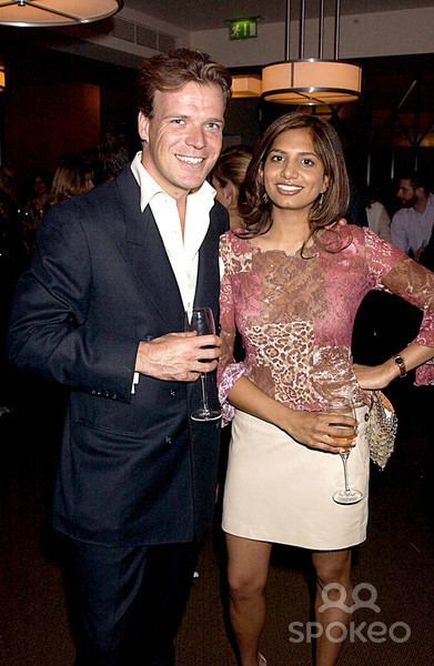 Joel Cadbury smiling with Divia Lalvani while holding a glass of wine