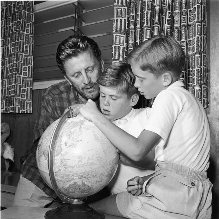 Kirk Douglas looks at a globe with two of his sons, Joel Douglas and Michael Douglas