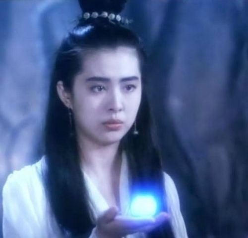 Joey Wong as Nip Siu-sin holding a glowing object and wearing a while chinese garment in a scene from A Chinese Ghost Story, 1987.