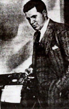 John Augustus Larson with a serious face beside a polygraph, wearing a suit, long sleeves, and necktie.
