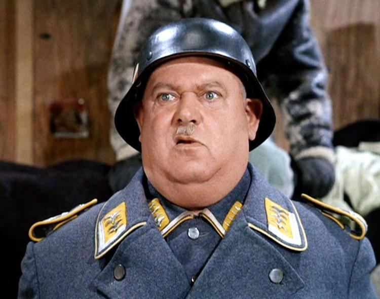 John Banner as Sergeant Hans Schultz, wearing a black helmet, gray and yellow coat and long sleeves in a scene from the 1965 tv-series, Hogan's Heroes