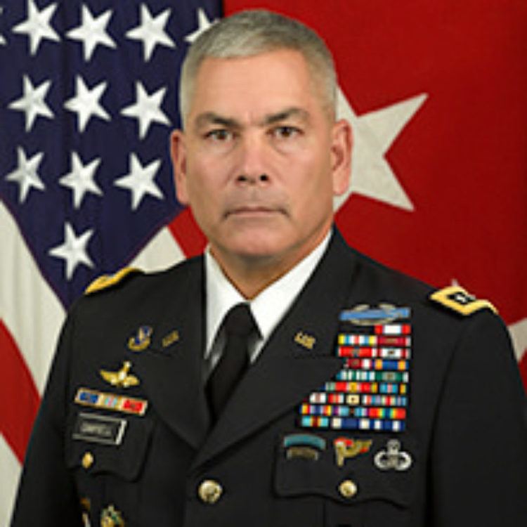 John F. Campbell wearing a military coat with badges, white long sleeves, and a black necktie