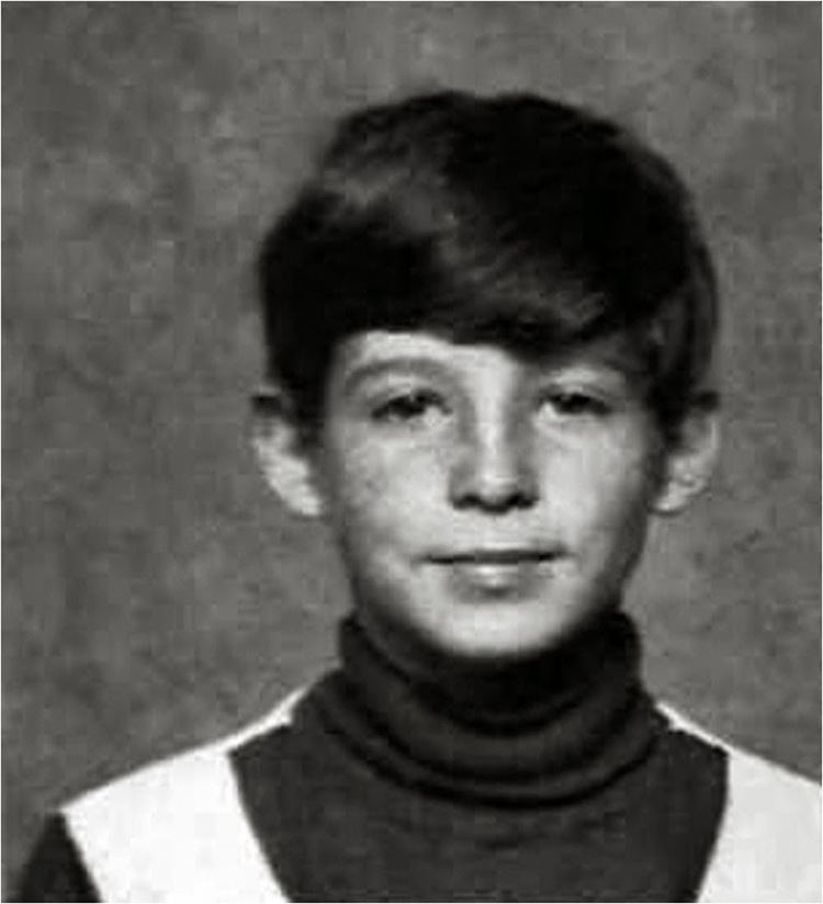 Young John Joubert smiling while wearing a turtle neck sweater