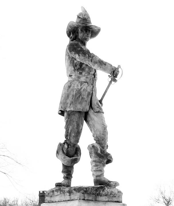 A monument of John Mason holding a sword, wearing a hat, coat, pants, and boots.