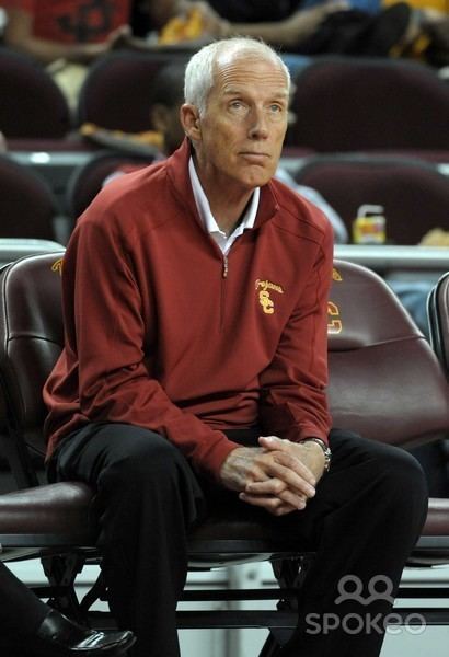 John McKay, Jr. wearing a red jacket and black pants while sitting on a chair.